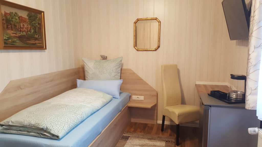 Zimmer mit Bett, Schreibtisch und Stuhl, Fernseher, Spiegel und Wasserkocher