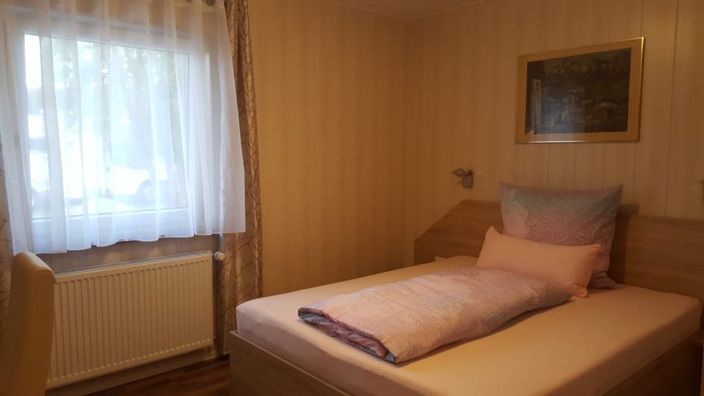Zimmer mit großem Bett, Fenster und Heizkörper